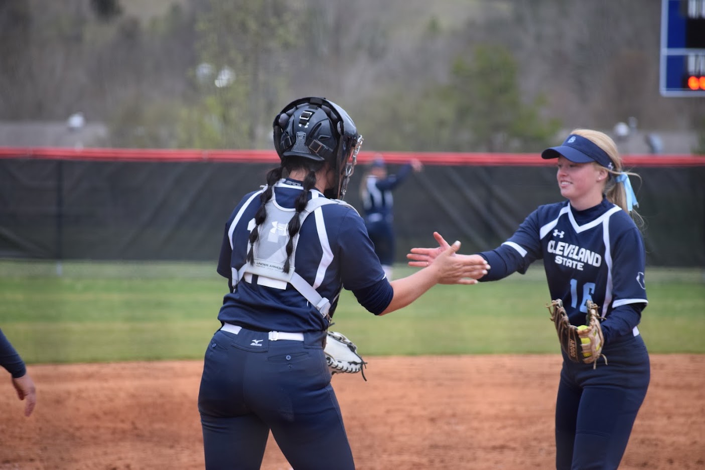 Two women high-five during softball game.