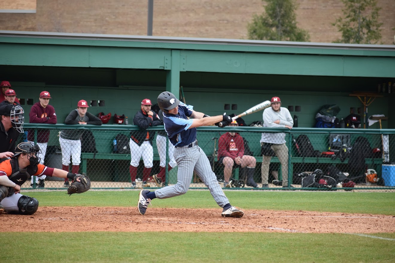 Baseball player swings at pitch.