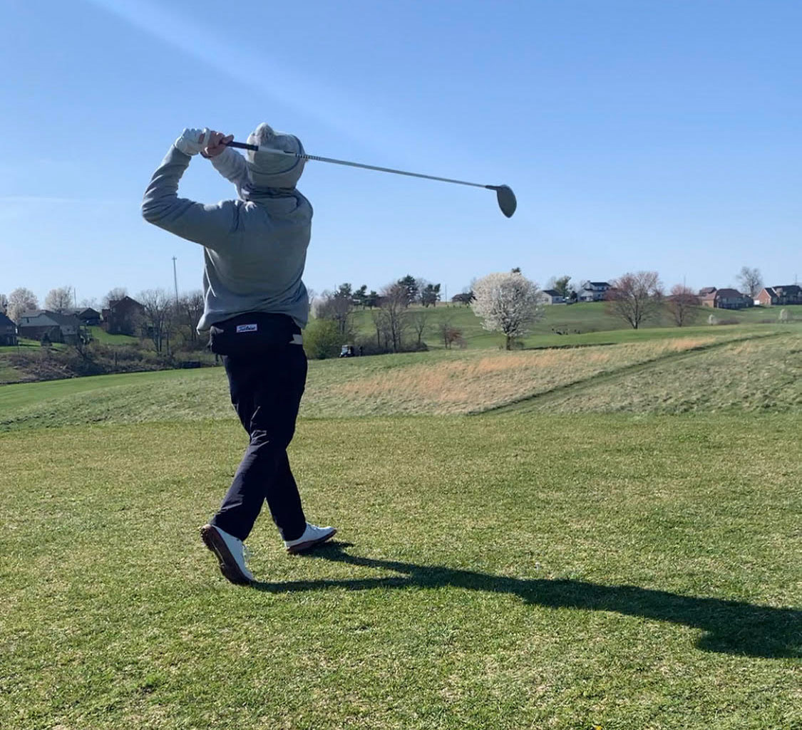 Player swings at golf ball.